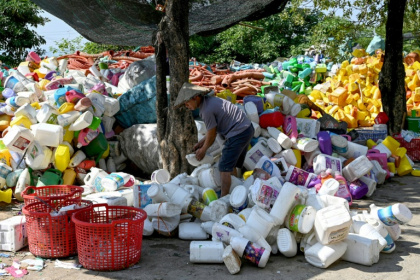A worker handling plastic bottles before they can be melted into tiny pellets for reuse - Nhac NGUYEN (AFP)